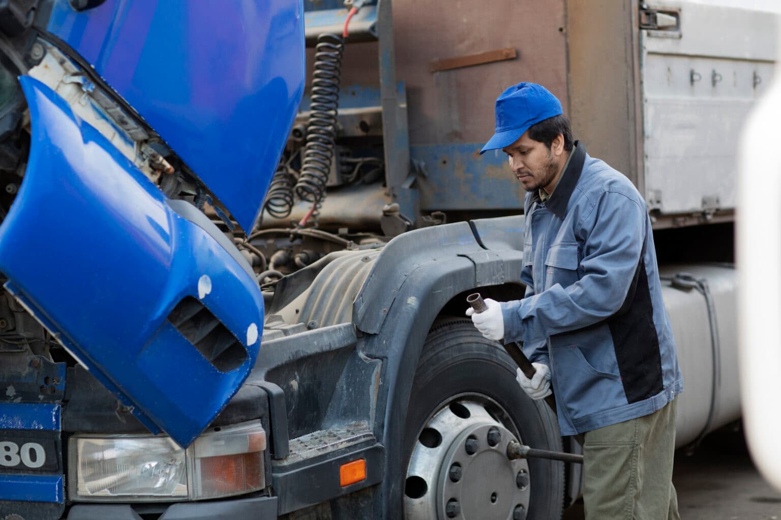 Techniker prüft einen LKW mit geöffneter Front.